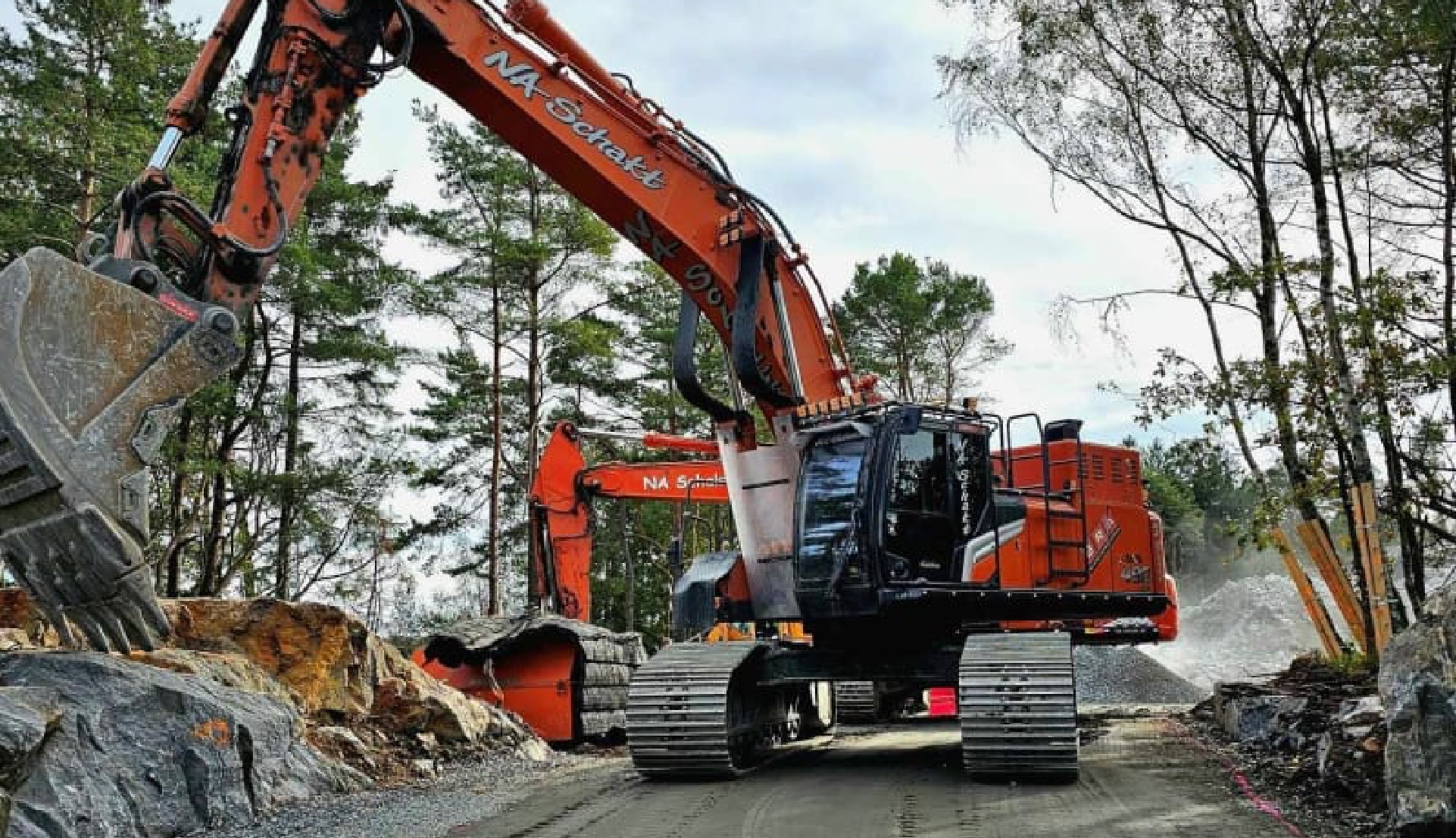 Orange grävmaskin arbetar i bergtäkt